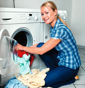 Frau lädt Wäsche in die Waschmaschine