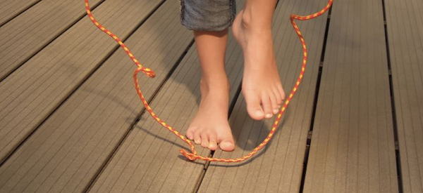 Foto: Kinderfüße mit Springseil auf Terrassen-Dielen