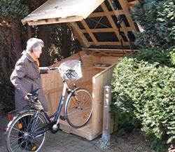 Ältere Dame schiebt Fahrrad in die Fahrrad-Garage