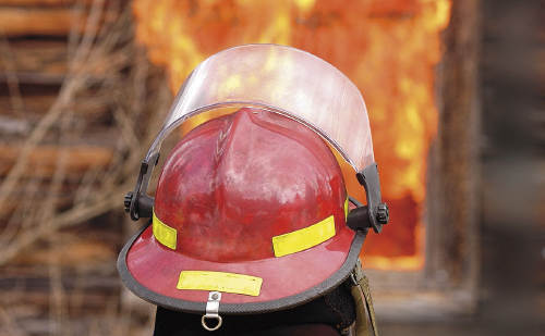 Feuerwehrmann vor brennendem Haus
