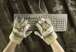 Hände mit Arbeitshandschuhen bedienen eine Computertastatur
