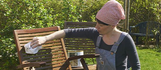 Frau beim Ölen eines Gartenstuhls