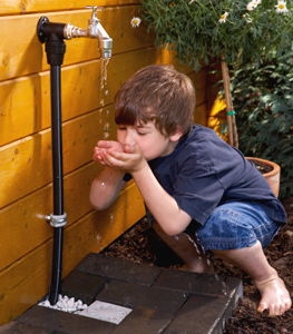 Junge trinkt aus Wasserhahn