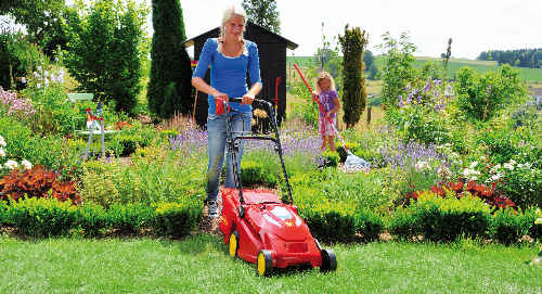 Frau mit Rasenmäher im Garten