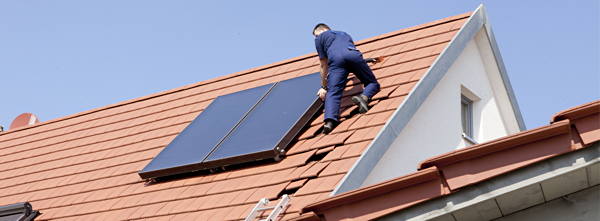 Handwerker bringt Sonnenkollektoren auf dem Dach an