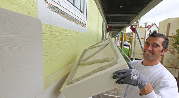 Foto: Arbeiter klebt Dämmplatte an Fassade