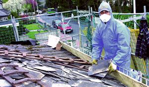 Arbeiter in Schutzkleidung entfernt Dachplatten