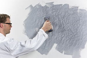 Mann spachtelt Wand in Betonoptik