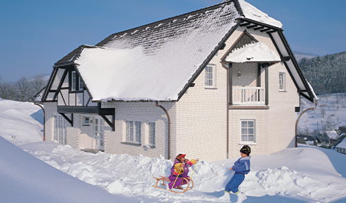 Kinder spielen vor schneebedecktem Haus