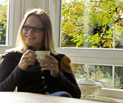 Frau beim Kaffeetrinken vor dem Fenster