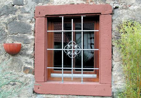 (Foto: mit Ziergitter versehenes Fenster in Bruchsteinwand) 