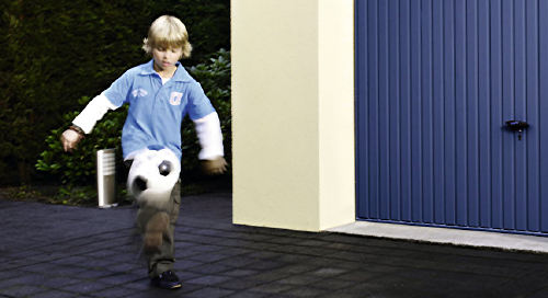 Junge spielt Fußball vor Garagentor