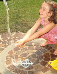 Mädchen spielt unter Wasserstrahl der Gartendusche