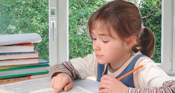 Foto: Mädchen macht Hausaufgaben, im Hintergrund Fenster mit Klimagriff