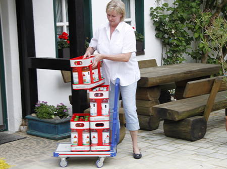 Foto: Frau transportiert Getränkekisten an die Haustür