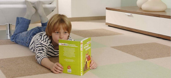 Kind liegt auf Teppichboden und liest